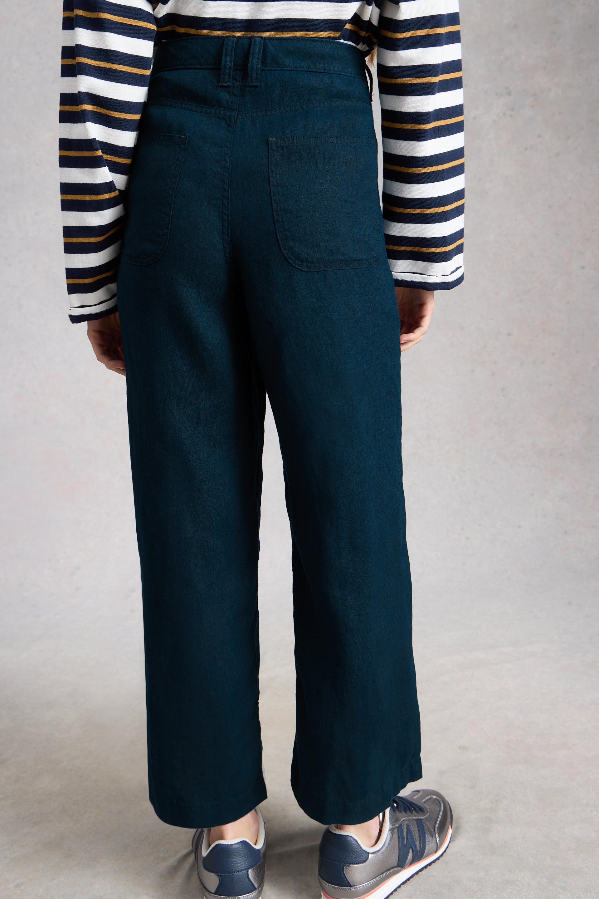 Person wearing wide leg linen trousers and a striped shirt against a plain background