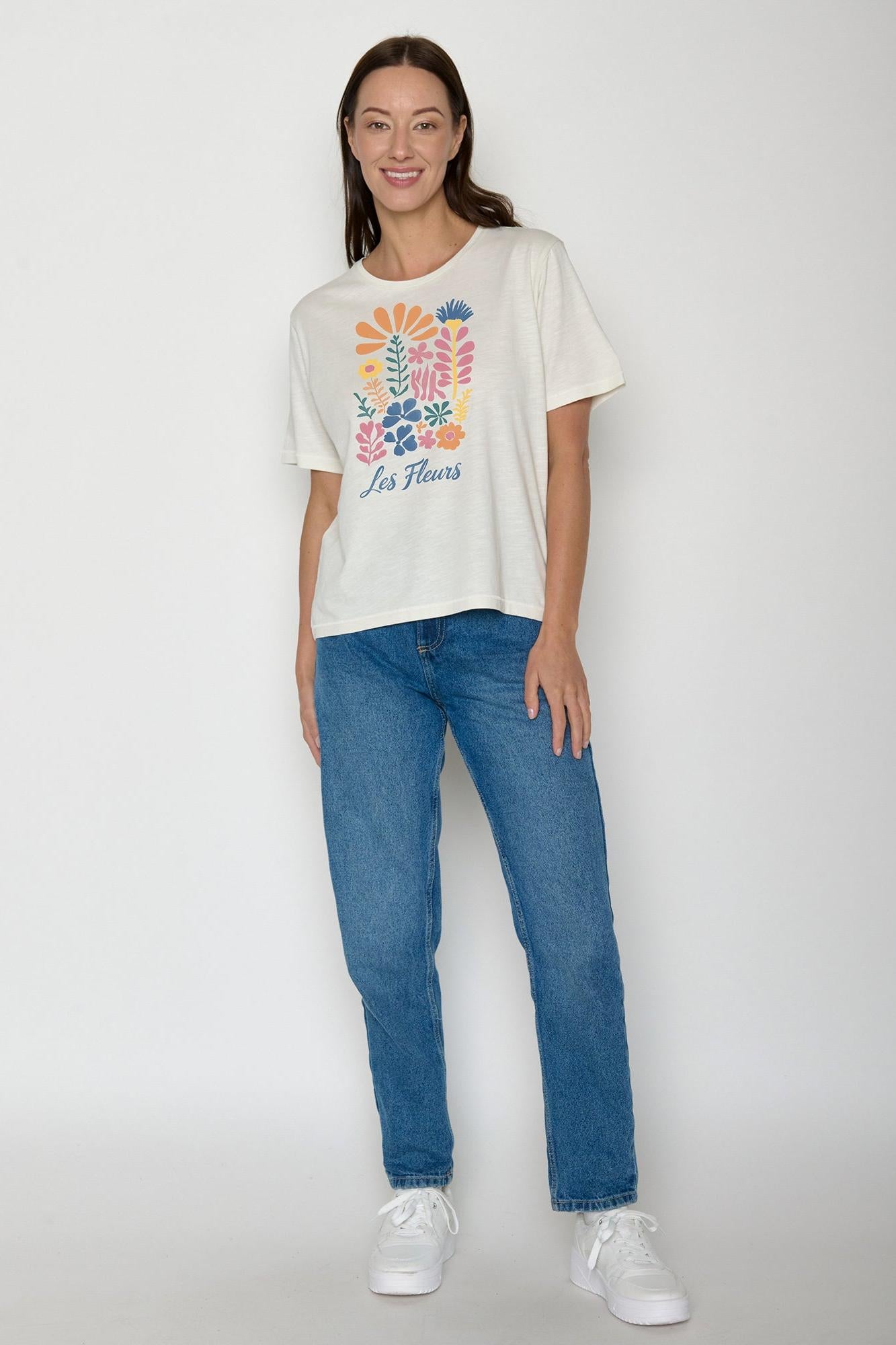 Woman wearing an organic cotton white t-shirt with colourful floral design and blue slim jeans