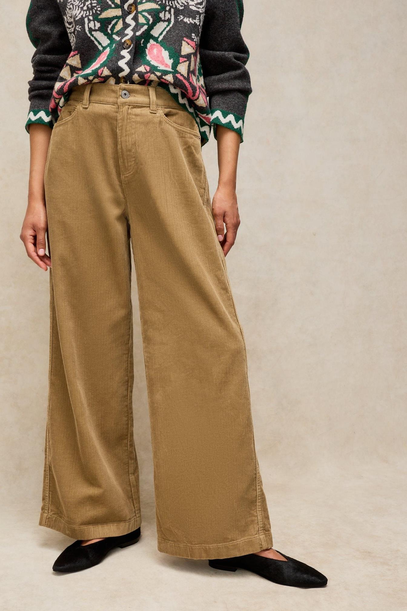 Woman wearing beige White Stuff cord trousers with a patterned cardigan against a plain studio background.