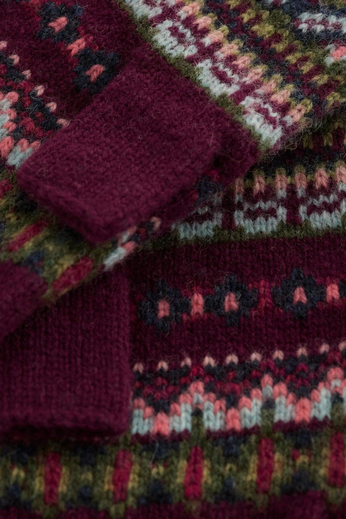 Close up of Seasalt Cornwall women's knit wool gloves with a dark red Fair Isle patterned design.