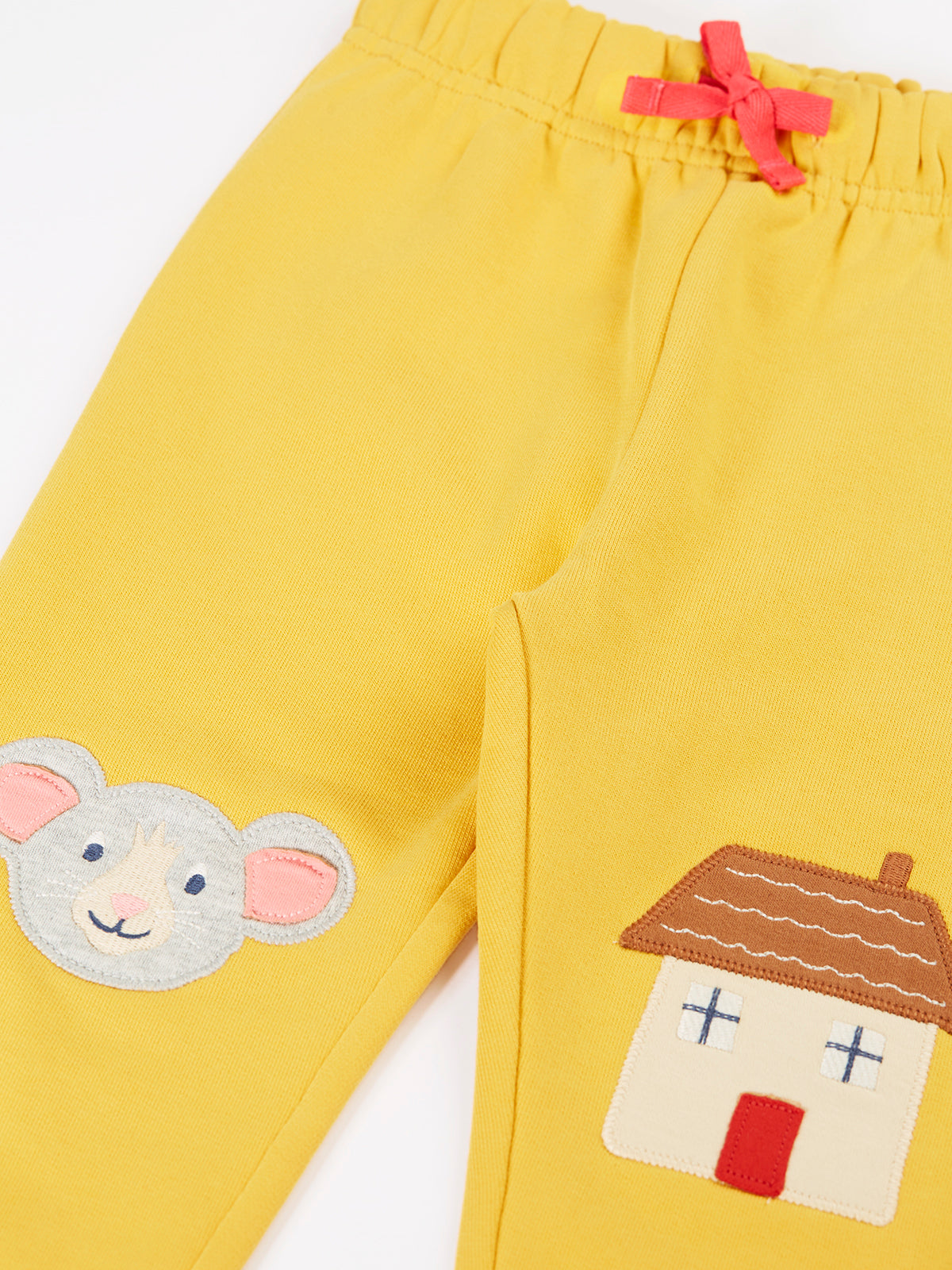 Bright yellow Frugi organic cotton joggers featuring mouse and house applique designs for girls.