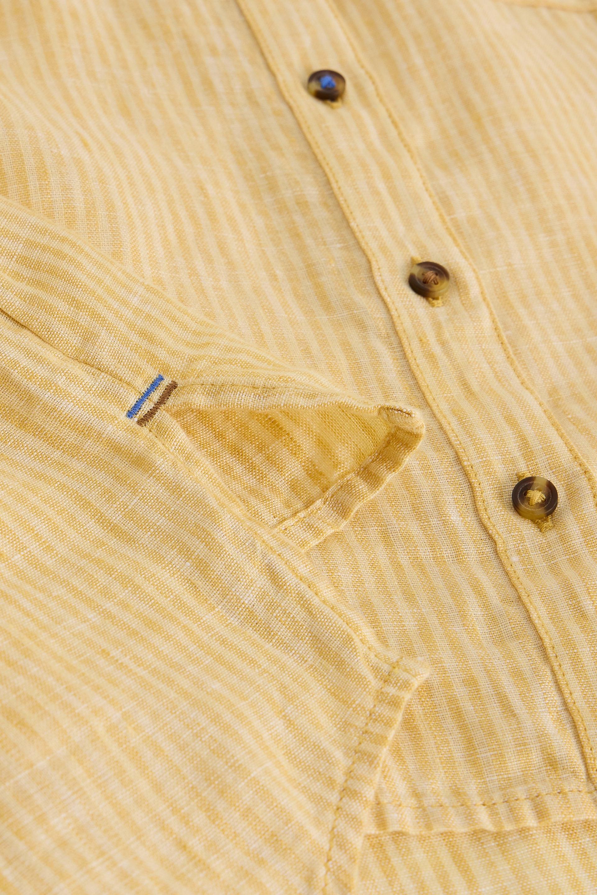 Close-up of a yellow and white striped linen shirt showing buttons and cuff detail.