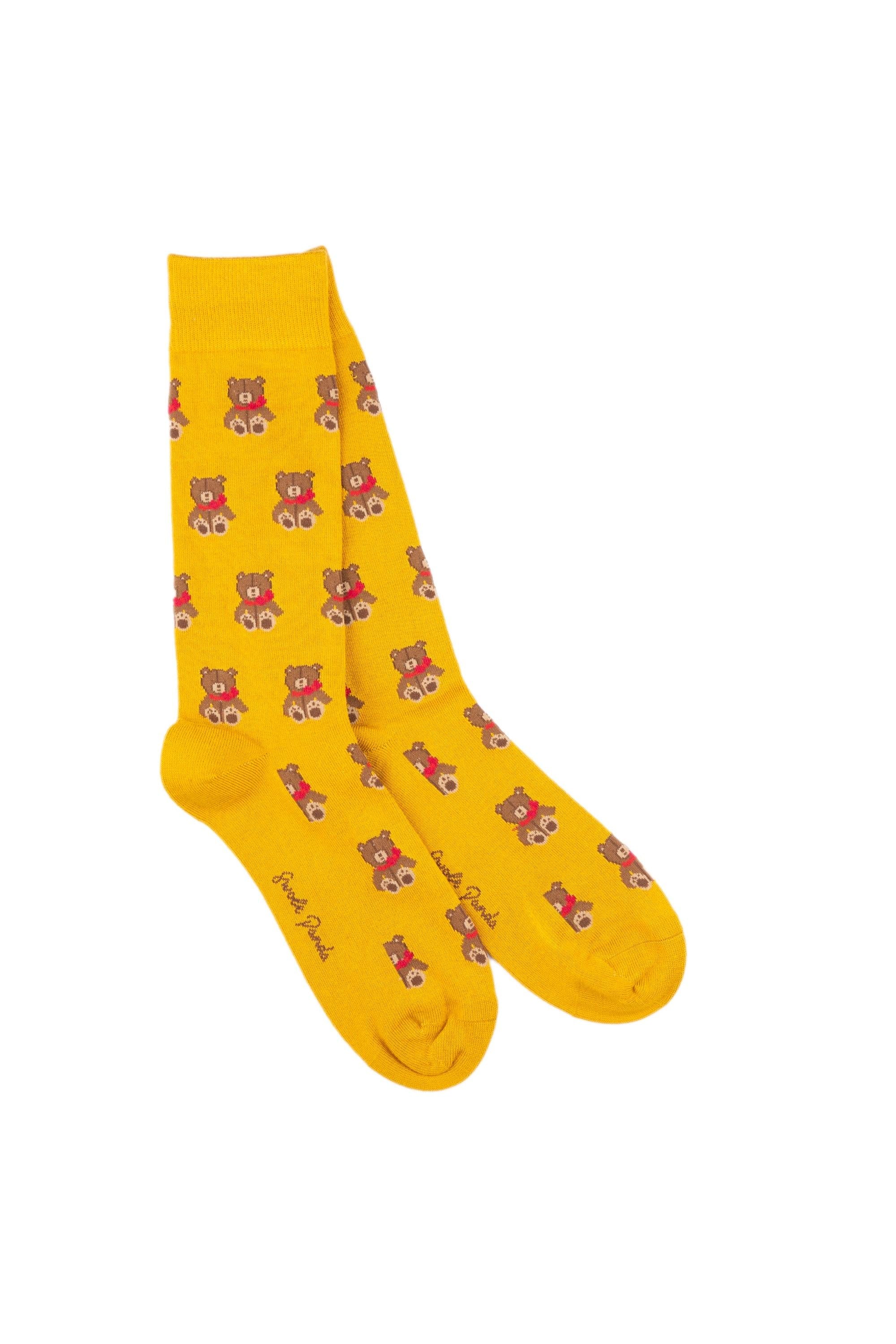 A pair of yellow fun socks featuring a repeating teddy bear pattern isolated on a white background.