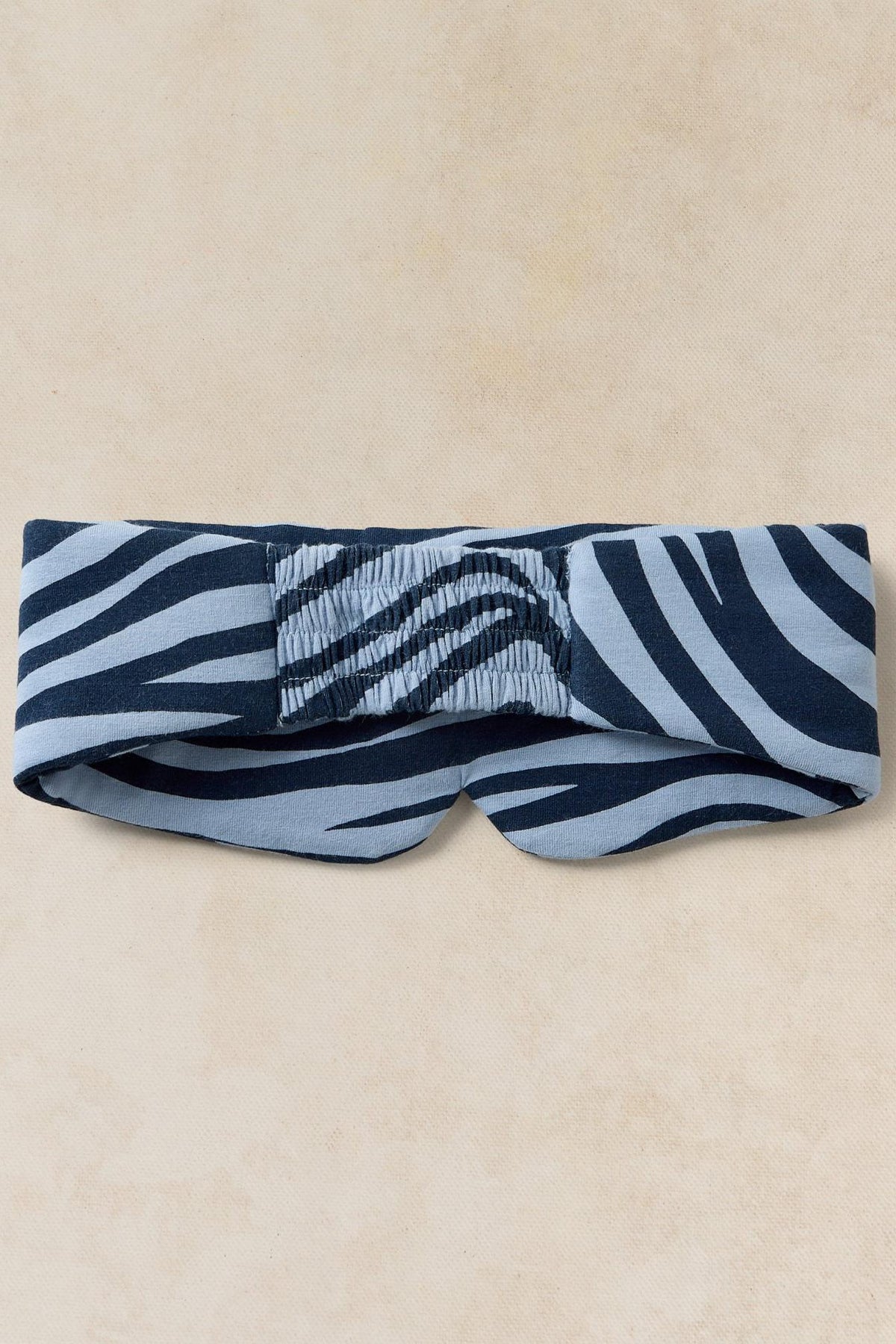 A White Stuff sleep mask featuring a blue and dark navy zebra print pattern on a neutral background.